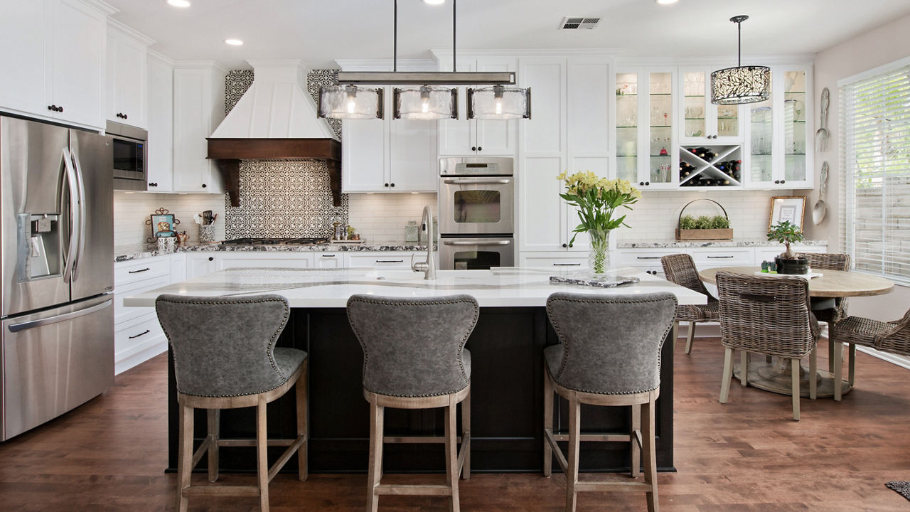 Three gray stool high chairs in front of an island with a Cambria Skara Brae quartz countertop. 