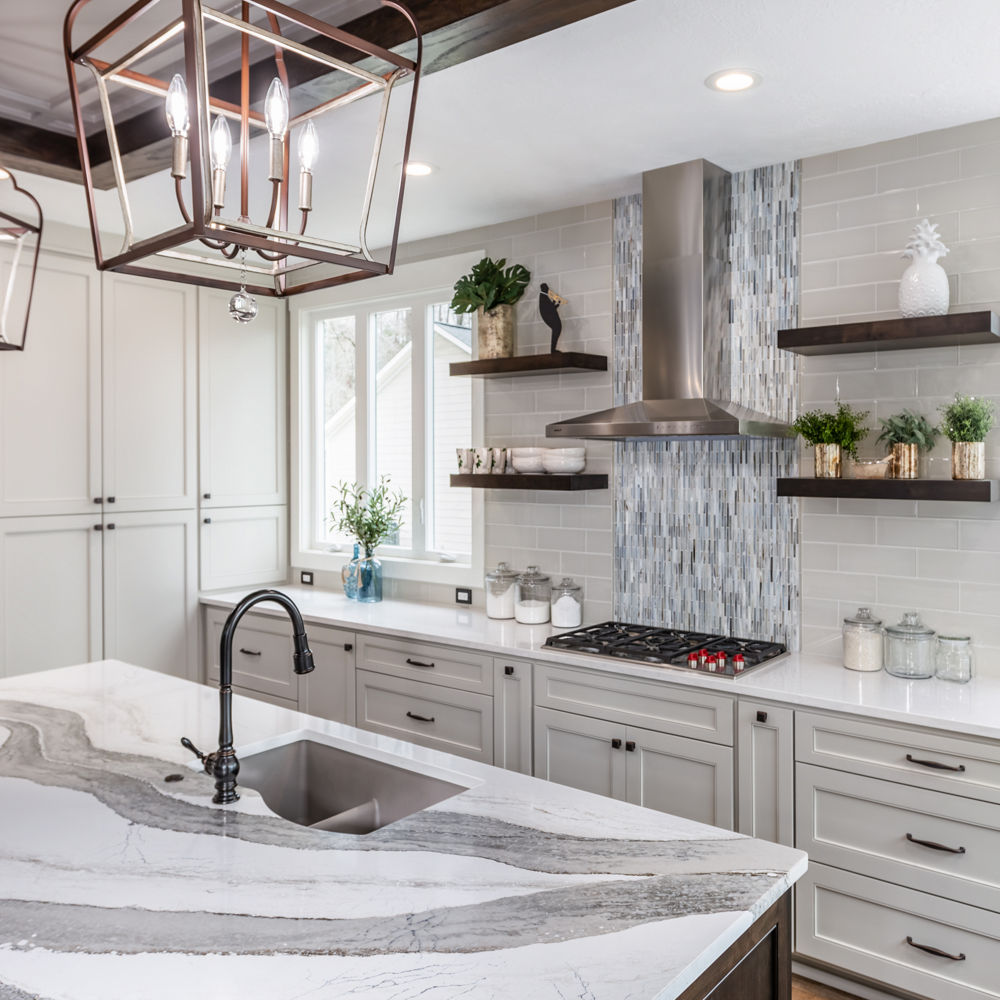 A bright, white kitchen with an island featuring a counter with a Cambria Skara Brae quartz countertop.