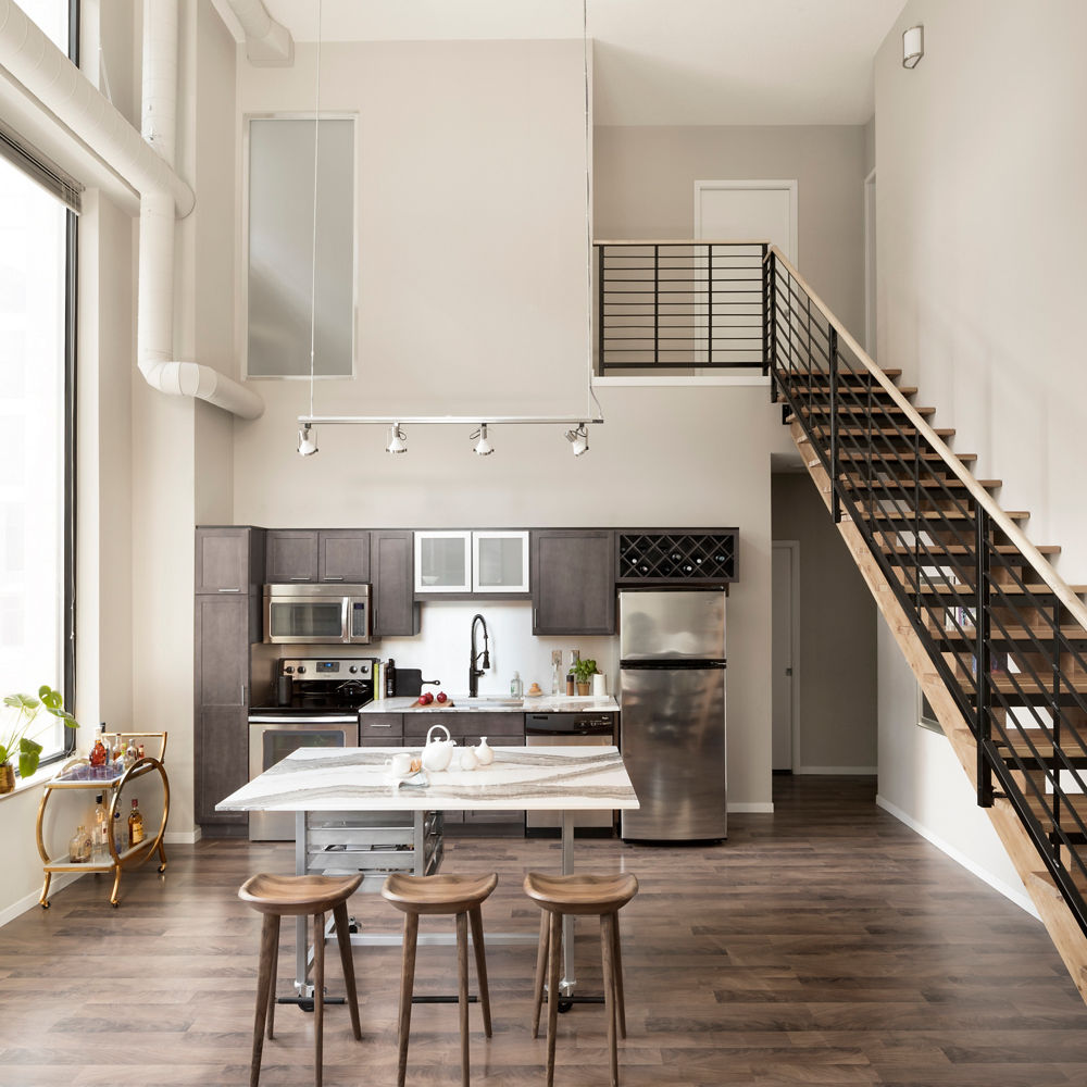 An open-concept loft kitchen with taupe gray cabinetry and Cambria Quartz Skara Brae countertops.