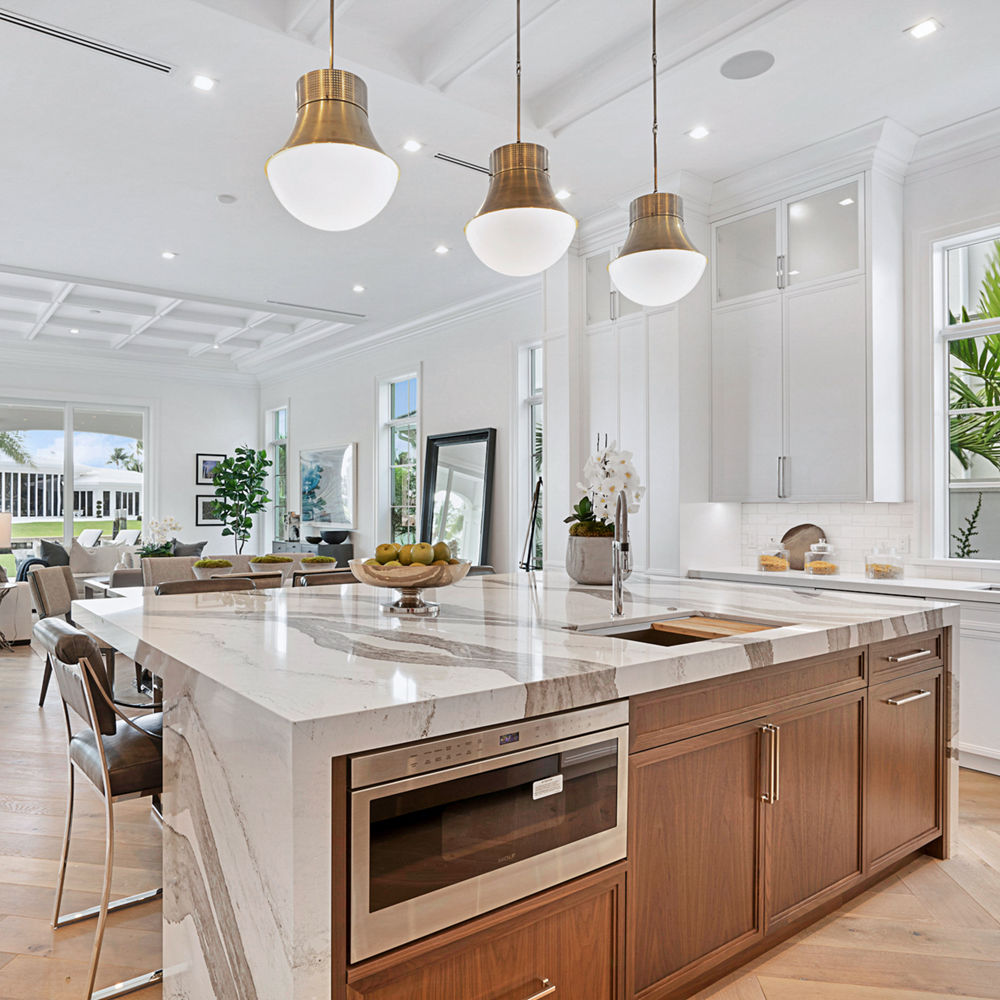 Stunning white kitchen with wood island featuring Skara Brae quartz.