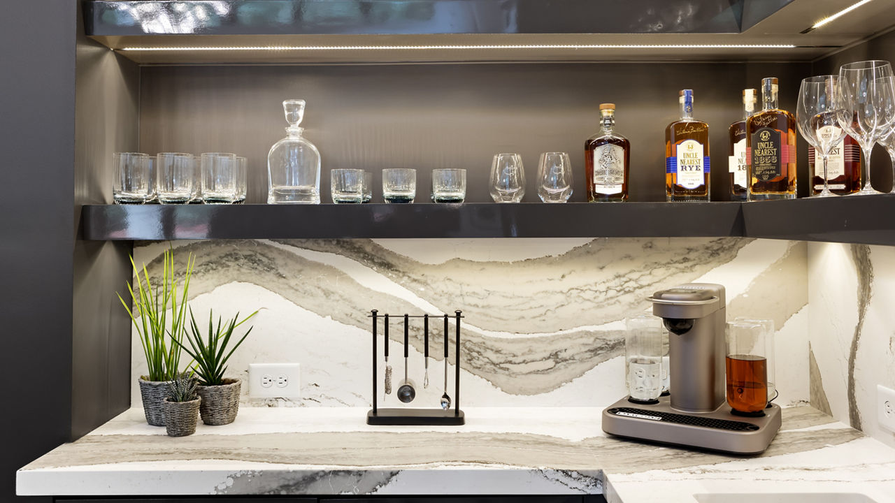 Counter with two shelves featuring various glasses and a base counter featuring a Cambria Skara Brae quartz countertop.