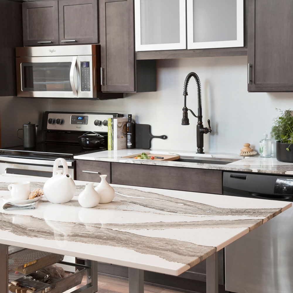 a gorgeous kitchen with gray-brown cabinets and a center island topped with white quartz countertops. 