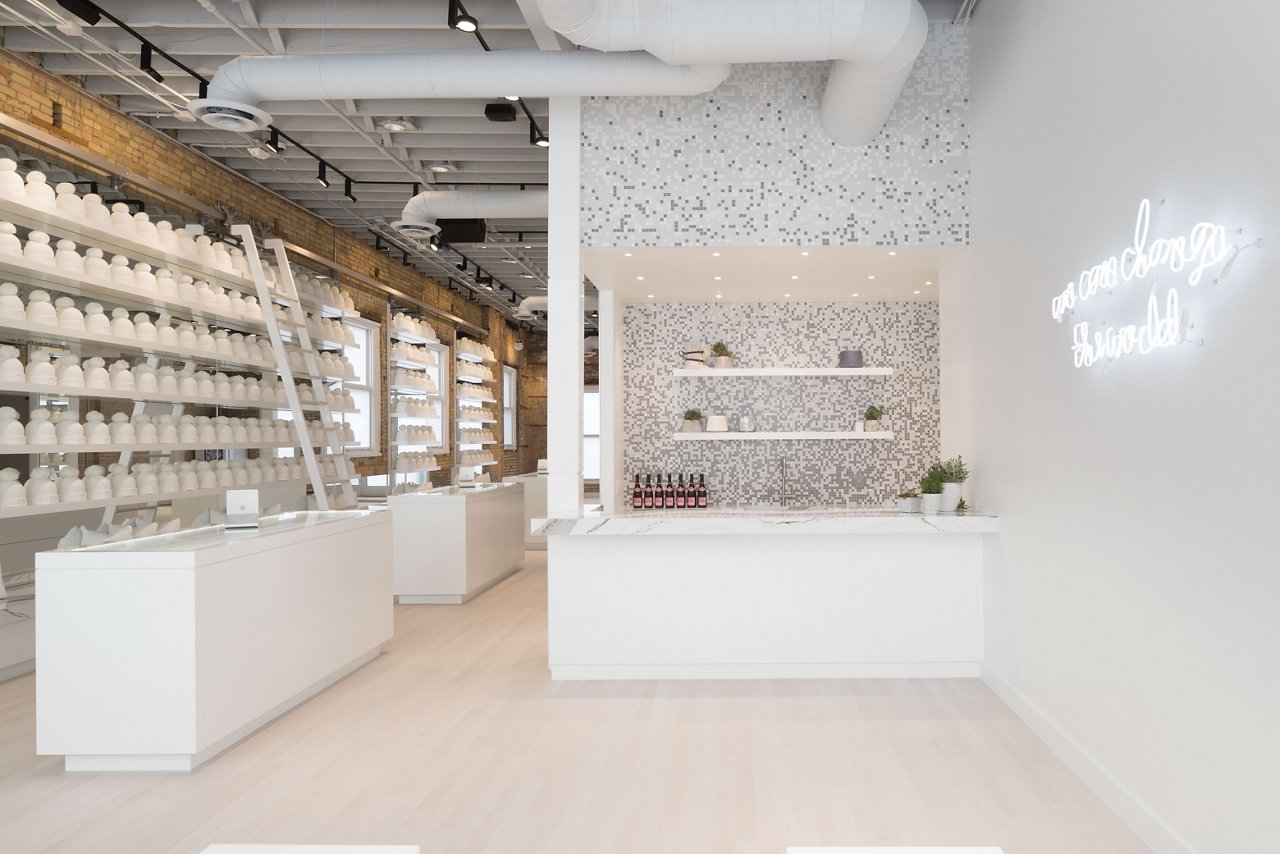 A kitchenette with white cabinets, white and gray veined quartz countertops, and open shelving.