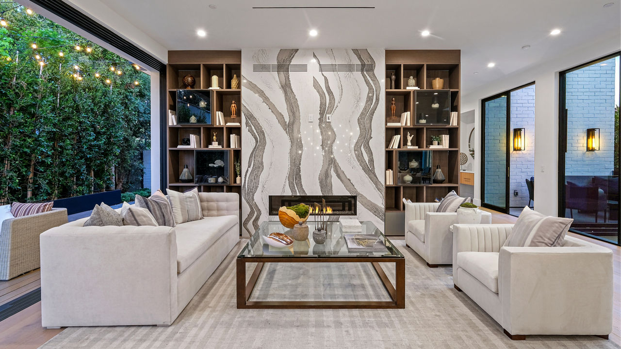 Living room featuring two white couches, a glass table, and a fireplace surrounded by a wall with a Cambria Skara Brae quartz surface.