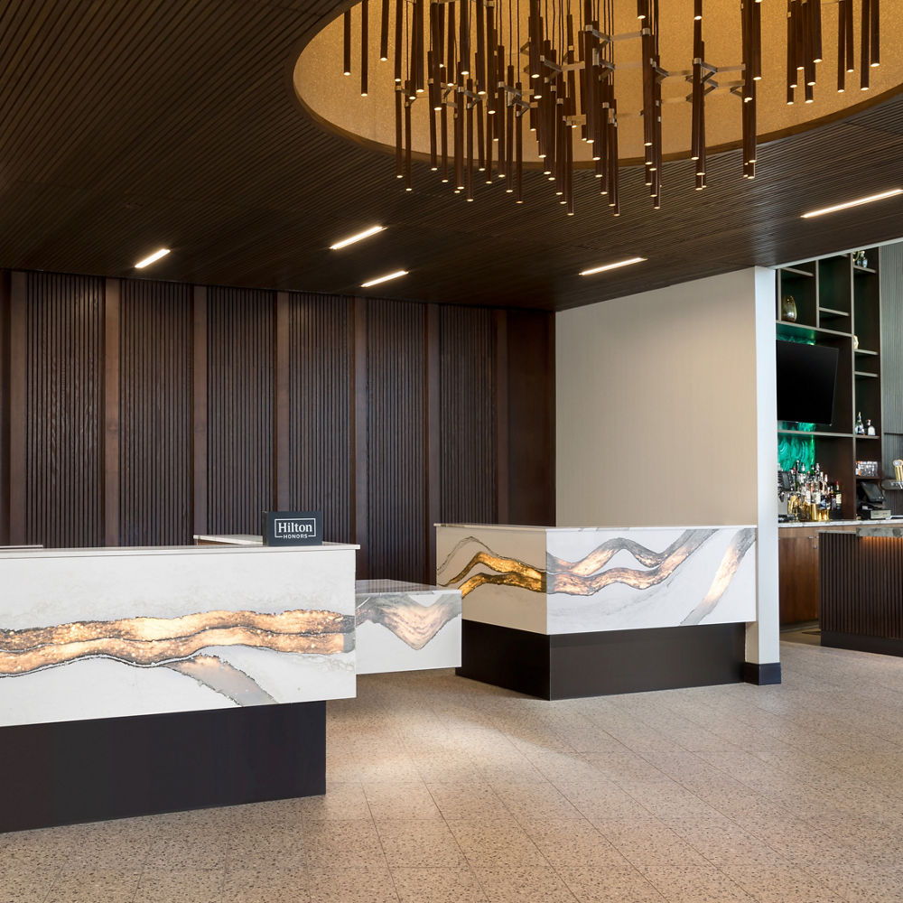 A lobby reception desk made from Cambria Skara Brae™ quartz with a backlit feature.