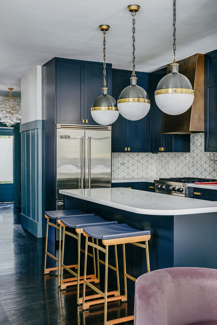 a gorgeous blue kitchen with white quartz countertops, dark wooden floors, cobalt blue cabinets, and gold accents.