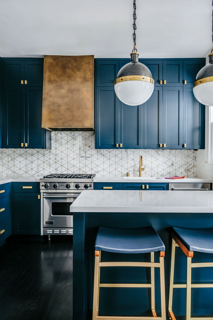 A luxurious blue kitchen with cobalt blue cabinets, gold hardware, white quartz countertops, and a unique tile backsplash.