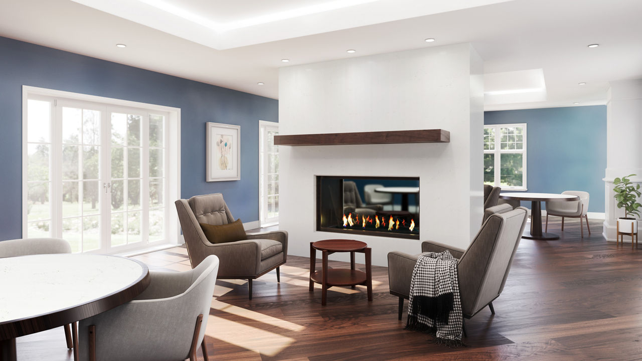 a living room with white quartz fireplace with wooden mantel, two gray chairs and an end table, blue painted walls, white trimmed windows, and wooden flooring.