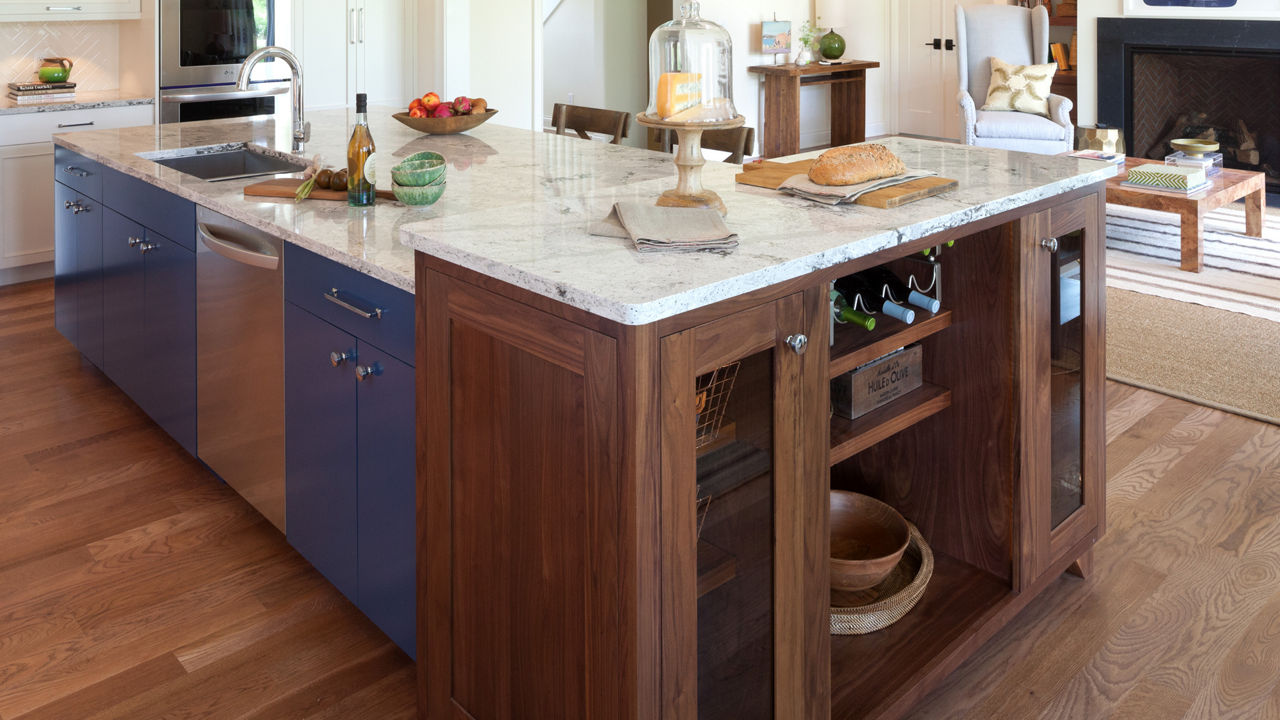 A warm kitchen with an island featuring a counter with Cambria Summerhill quartz countertops.