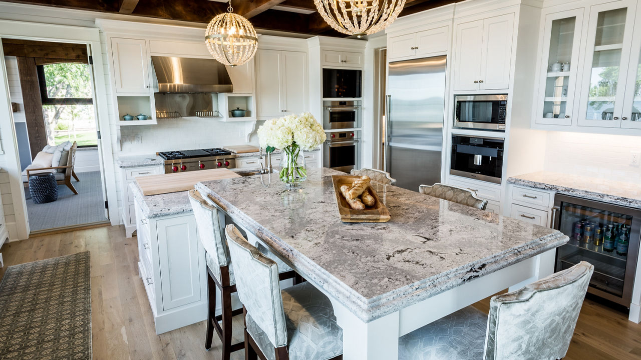 A kitchen with white cabinets, wooden beams on the ceiling, and Summerhill quartz countertops 