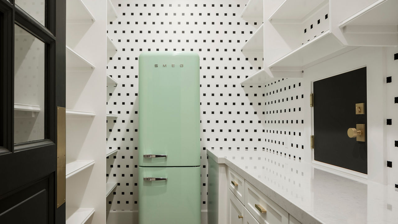 A butler's pantry with black and white patterned walls, Swanbridge quartz countertops, and a green SMEG refrigerator.