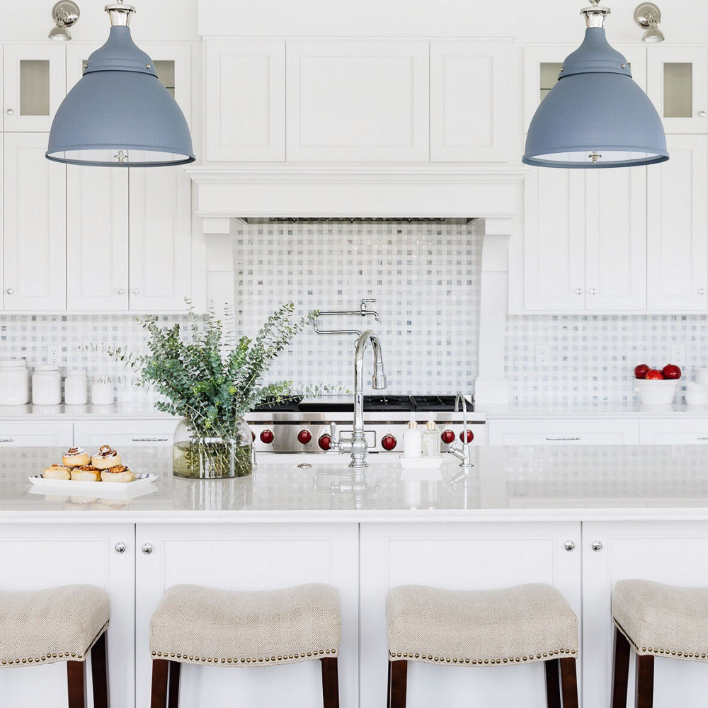 White kitchen with matte blue light fixtures and Swanbridge countertops.