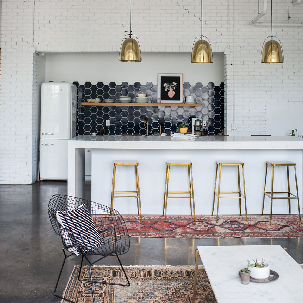 a kitchen with fireclay tile backsplash, white quartz countertops, a white fridge, and exposed brick walls. 