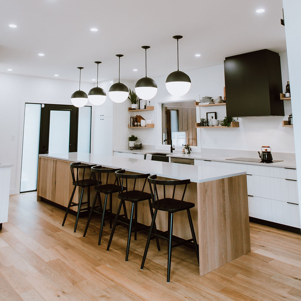 Four black stools stand in front of a kitchen island with a Cambria Templeton quartz countertop.