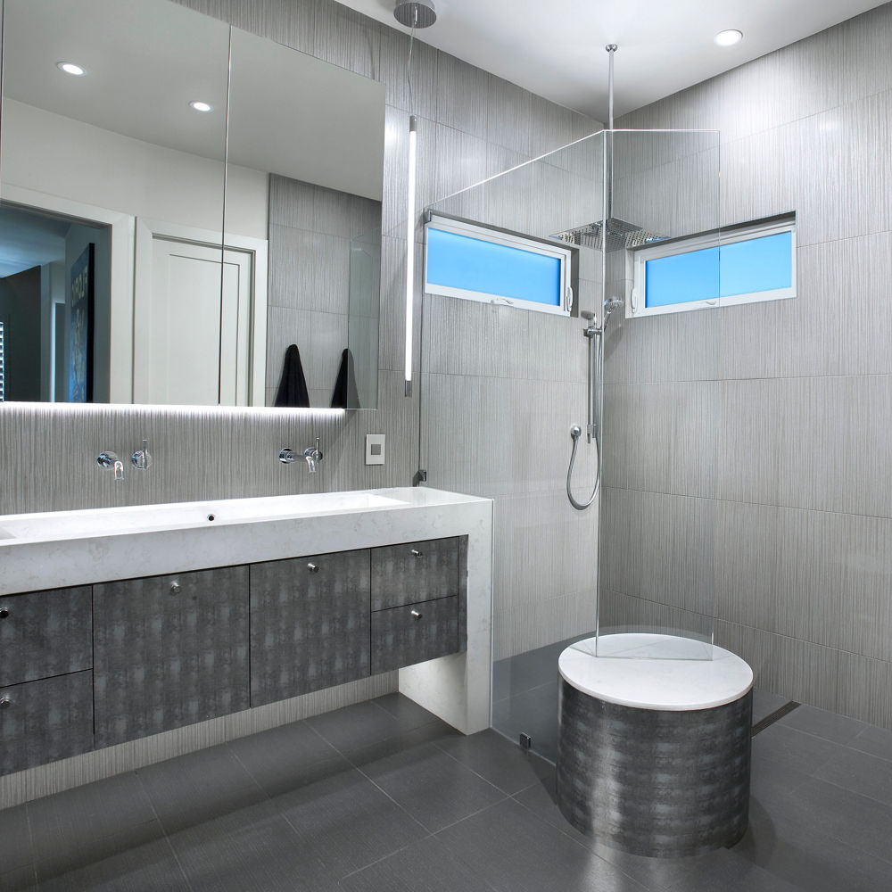 A sleek bathroom with gray tile flooring and siding with a counter featuring a Cambria Torquay quartz countertop.