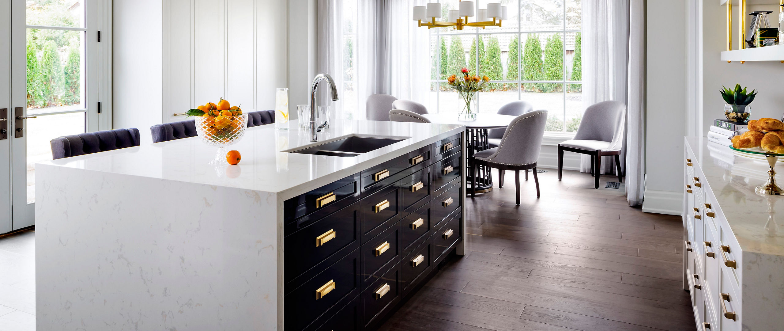 Kitchen featuring an island with Cambria Torquay quartz countertops and siding beside a dining table.