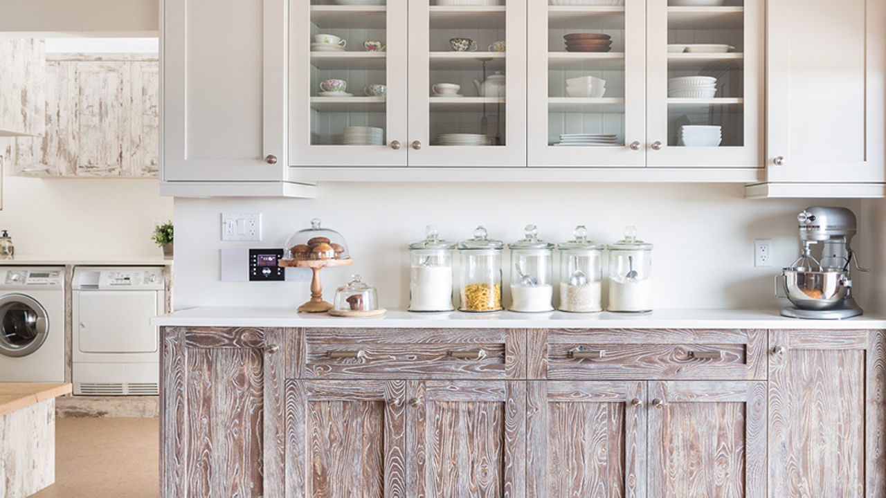 A kitchen with brown ash cabinets that give a rustic-chic look with Cambria Quartz Ella countertops and cream cabinets.