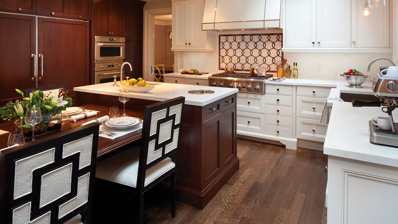 a traditional kitchen with white cabinets, white quartz countertops, a center island with a built-in table.