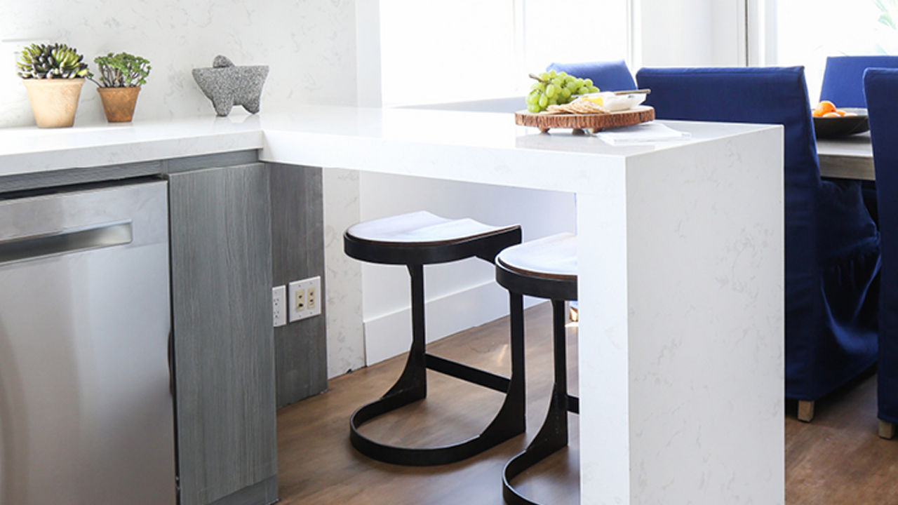 a modern kitchen with a white quartz waterfall-edge peninsula that is perfect for eating meals at