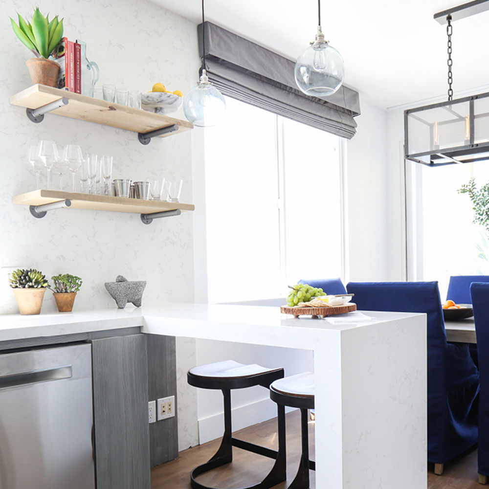 a modern kitchen with a white quartz waterfall-edge peninsula that is perfect for eating meals at