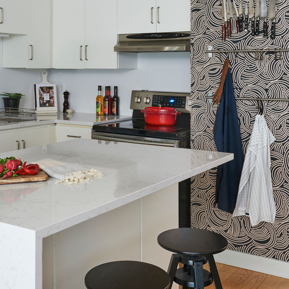 Kitchen with a counter and island with Cambria Torquay quartz countertops and a statement wall with clothes hangers.