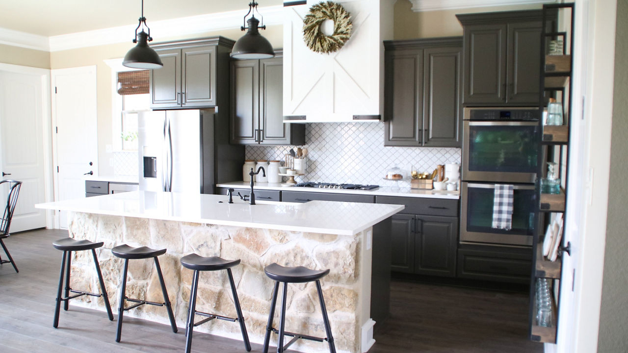 A kitchen with black stools in front of an island with Cambria Torquay quartz countertops.