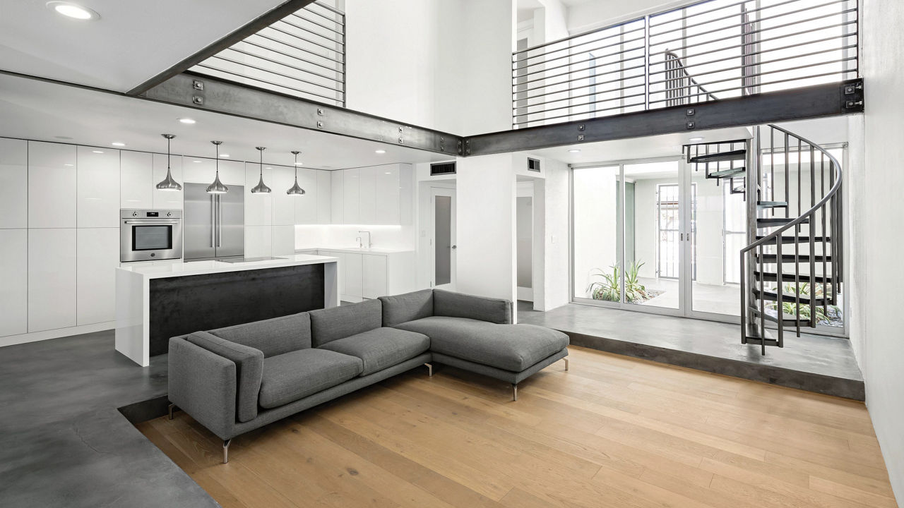 A contemporary kitchen and living room featuring white cabinets and white quartz countertops.