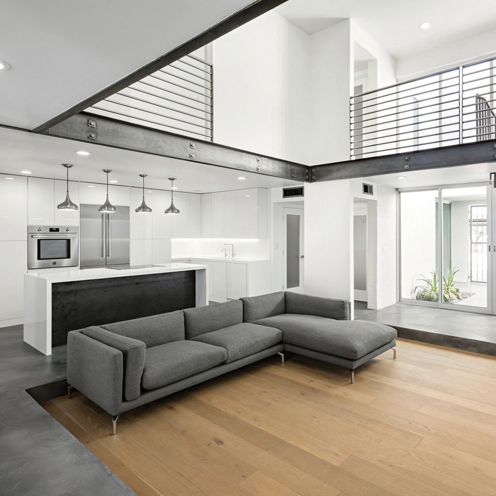 A contemporary kitchen and living room featuring white cabinets and white quartz countertops.