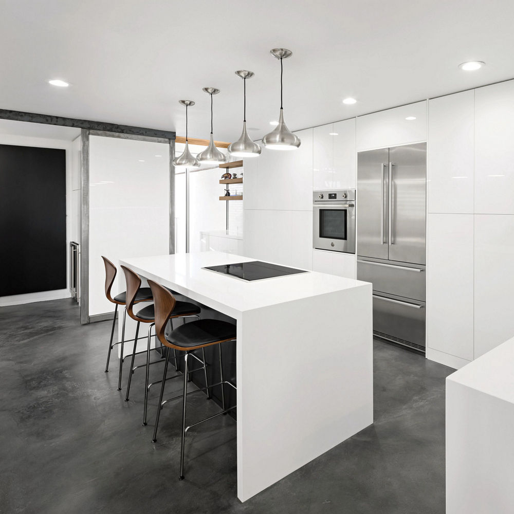 A modern kitchen with white cabinets, white quartz double island waterfall, black flooring, and stainless-steel appliances.