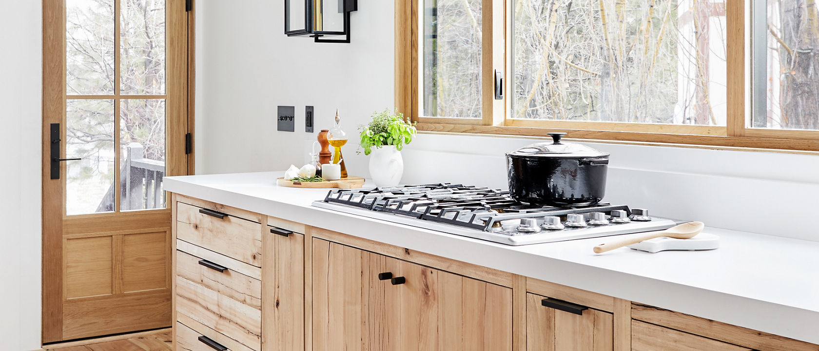 a bright and airy kitchen with oak cabinets, white quartz countertops, and wooden door and window.