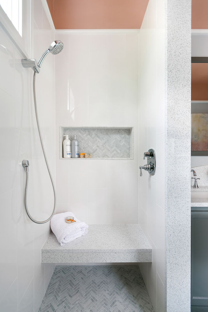 A shower made from white quartz with a shower seat, light green wall and floor tiles, and orange walls.