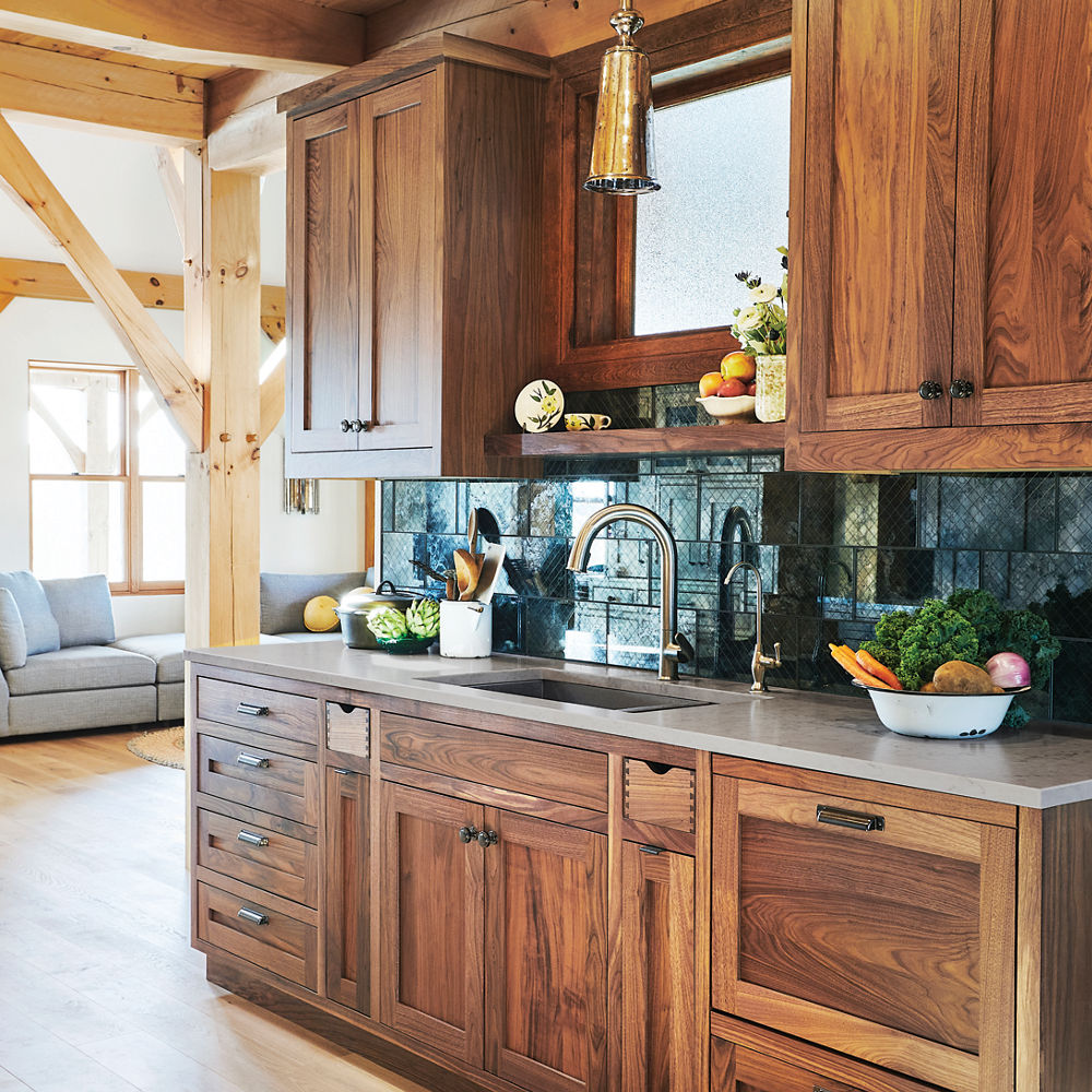 A kitchen with gorgeous wooden cabinets, white quartz countertops, wooden flooring, and wooden beams.